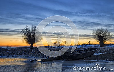 Old boat at sunset on the Danube river in winter Stock Photo