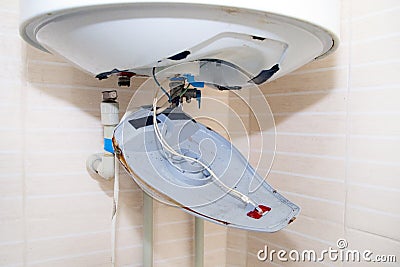Old boiler is broken, repair and installation of a new water heater. Hired mechanic eliminates breakdown Stock Photo