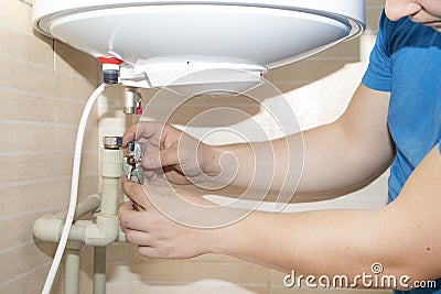 Old boiler is broken, repair and installation of a new water heater. Hired mechanic eliminates breakdown Stock Photo