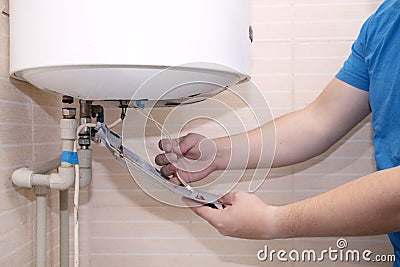 Old boiler is broken, repair and installation of a new water heater. Hired mechanic eliminates breakdown Stock Photo