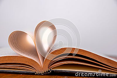 Old book and heart-shaped pages. White background. Wooden Table. Closeup. Copy space Stock Photo
