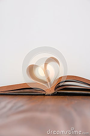 Old book and heart-shaped pages. White background. Wooden Table. Copy space Stock Photo