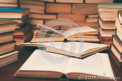 Old book in library with open textbook, stack piles of literature text archive on reading desk in school study class room Stock Photo