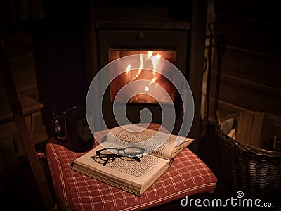 An old book, a mug and glasses in front of an woodstove Stock Photo