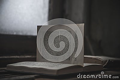 An old book with a torn page lies in an abandoned building. Gloomy atmosphere. An old book. Stock Photo