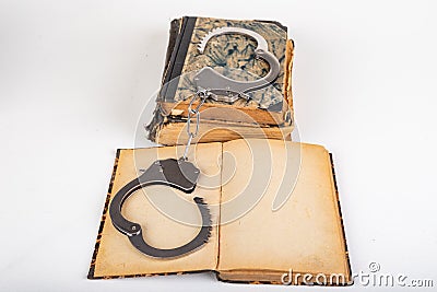 Old books and metal handcuffs. Literature and prison for bad words Stock Photo