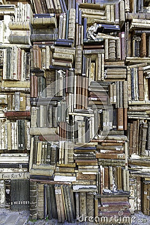 Old books piled on a wall, stacked in a disorderly fashion Stock Photo