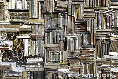 Old books piled on a wall, stacked in a disorderly fashion Stock Photo