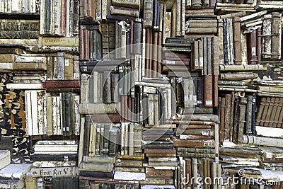 Old books piled on a wall, stacked in a disorderly fashion Stock Photo