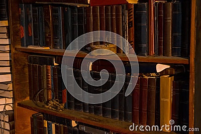 Old books stand on wooden shelves, shelving with books.on the shelf is an old, rusty lock and a bunch of keys, the concept of scie Stock Photo