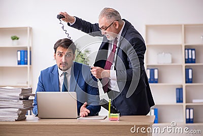 Old boss and young male employee in bullying concept Stock Photo