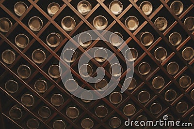 Old bottles of wine on the wall of dark wine cellar. Close-up. Background, pattern, texture. Abstract, design. Stock Photo