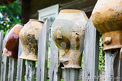 Old broken clay jugs on wooden fence Stock Photo