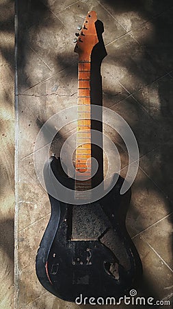 Old broken guitar in sunlight shadows Stock Photo