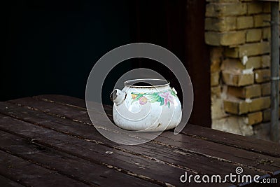 Old broken kettle standing on wooden table Stock Photo