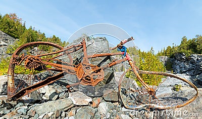 Old broken rusted bicycle in a rock quarry. Stock Photo