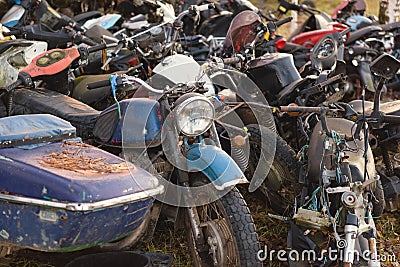 Old broken rusty bicycles, motorcycles, toy cars, engines, tires and wheels with spokes in the open air on the ground Stock Photo