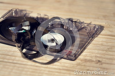 Old broken unwound compact cassette audio tape messed up on wooden background Stock Photo