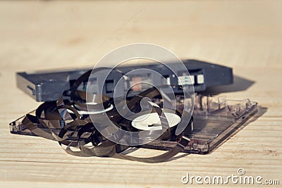 Old broken unwound compact cassette audio tape messed up on wooden background Stock Photo