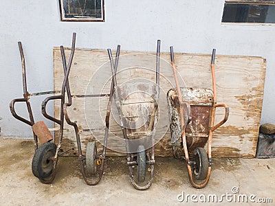 Old and broken wheelbarrows placed against the wall Stock Photo