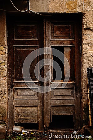 Old broken wooden brown door with empty bottles on the ground Stock Photo