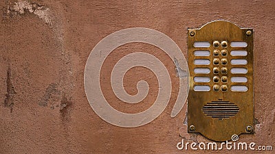 Old bronze intercom on an old wall with peeling paint. Ratio 16:9 Stock Photo