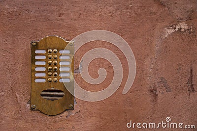 Old bronze intercom on an old wall with peeling paint. Stock Photo