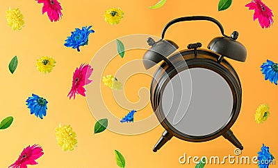 Old brown clock with blank space and colorful flowers flying on a orange background. Positive news, thinking and energy concept. Stock Photo