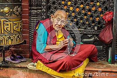 Old buddhist nun sits and begs in Kathmandu, Nepal Editorial Stock Photo