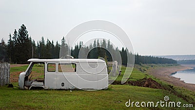 The old building of the Soviet machine lies on the green grass at the edge of the river. Stock Photo