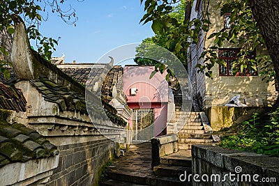 Old buildings by stone stairway on slope in sunny morning Stock Photo