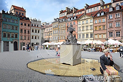 Old Busker sit down in front of The mermaid(Syren) Fountain,old town market place square in old town of Warsaw, Poland. Editorial Stock Photo