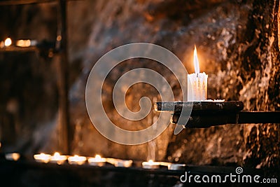 Old Candle In Church. Candle Light Flame Near Ancient Wall Stock Photo