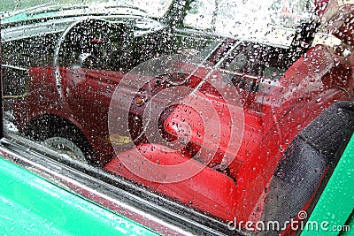 Old car. Red chairs and wheel. The window is covered by raindrops Stock Photo