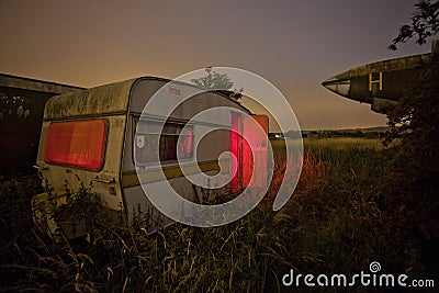 Old caravan in an overgrown field Stock Photo