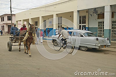 Old cars in Cuban village near the El Rincon driving past old store and villagers Editorial Stock Photo