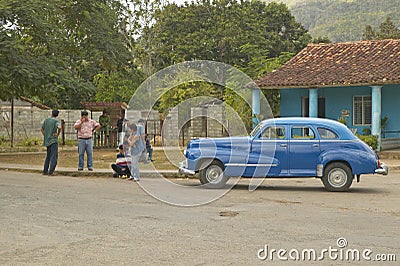 Old cars and three people in Cuban village in rural central Cuba Editorial Stock Photo