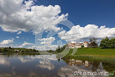 Old castle on green hill near lake with expressive sky background Stock Photo