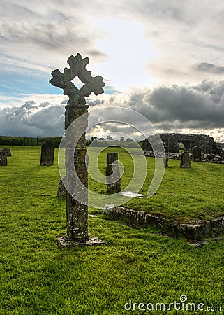 Old celtic stone cross on cemetery full of green grass Stock Photo