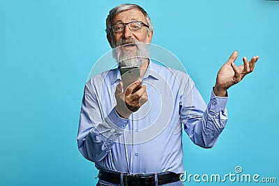 Old cheerful man with raised hand holding mobile phone Stock Photo