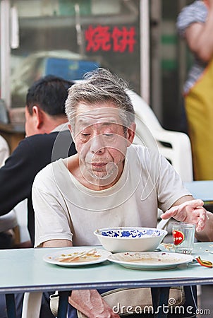 Old Chinese man eats in a neighborhood restaurant, Beijing, China Editorial Stock Photo