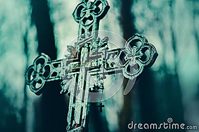 An old Christian tombstone cross stands at dusk in the cemetery, and rosaries hang on it. Death. Religion Stock Photo