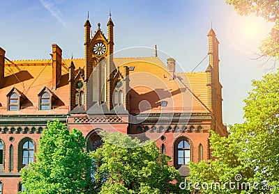 The old church is illuminated by the sun, the beautiful landscape of the brick building behind the trees Stock Photo