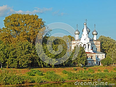 An old church standing on the river bank surrounded by trees Stock Photo