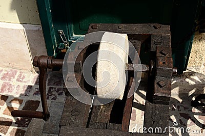 Vintage old grindstone wheel sharpening tool. round wheel set in wood frame. Stock Photo