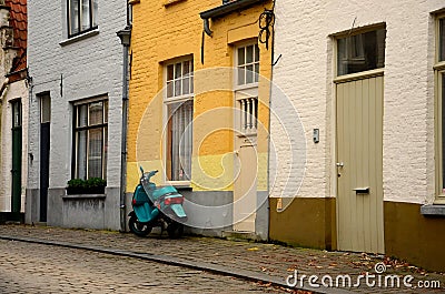 Old cobbled street, yellow wall and green scooter Stock Photo