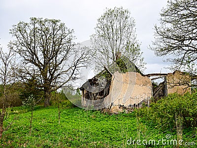 Old and collapsed country house, collapsed wall and old wooden logs Stock Photo