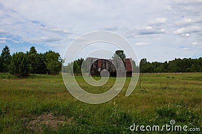 Old collapsed wooden house on a green field Stock Photo