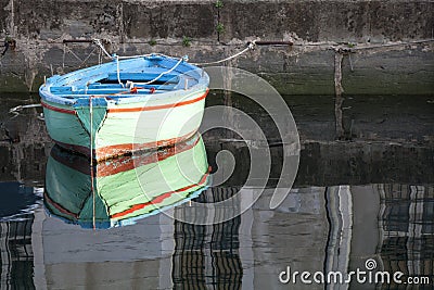 Old colored wooden boat in the water in a river with reflection Stock Photo