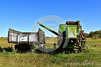 Old combine and grain truck parked in an overgrown meadow Stock Photo